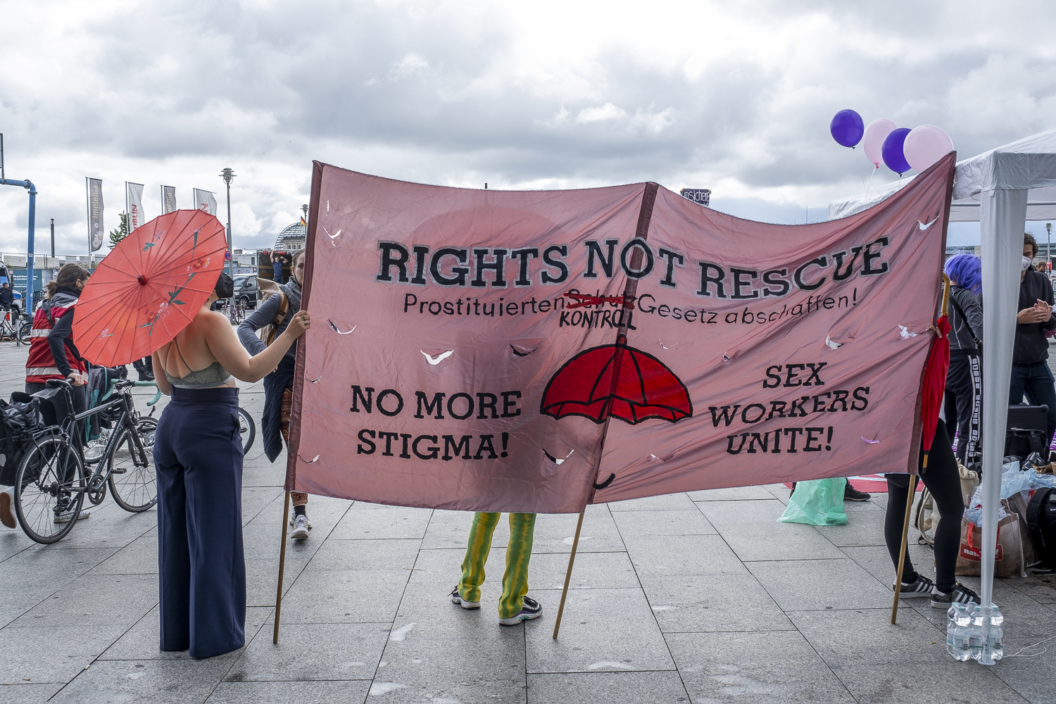 Großes Transpi auf einer Demo, Text u.a. Rights not rescue. No more Stigma. Sex workers unite. In der Mitte ein roter Regenschirm.