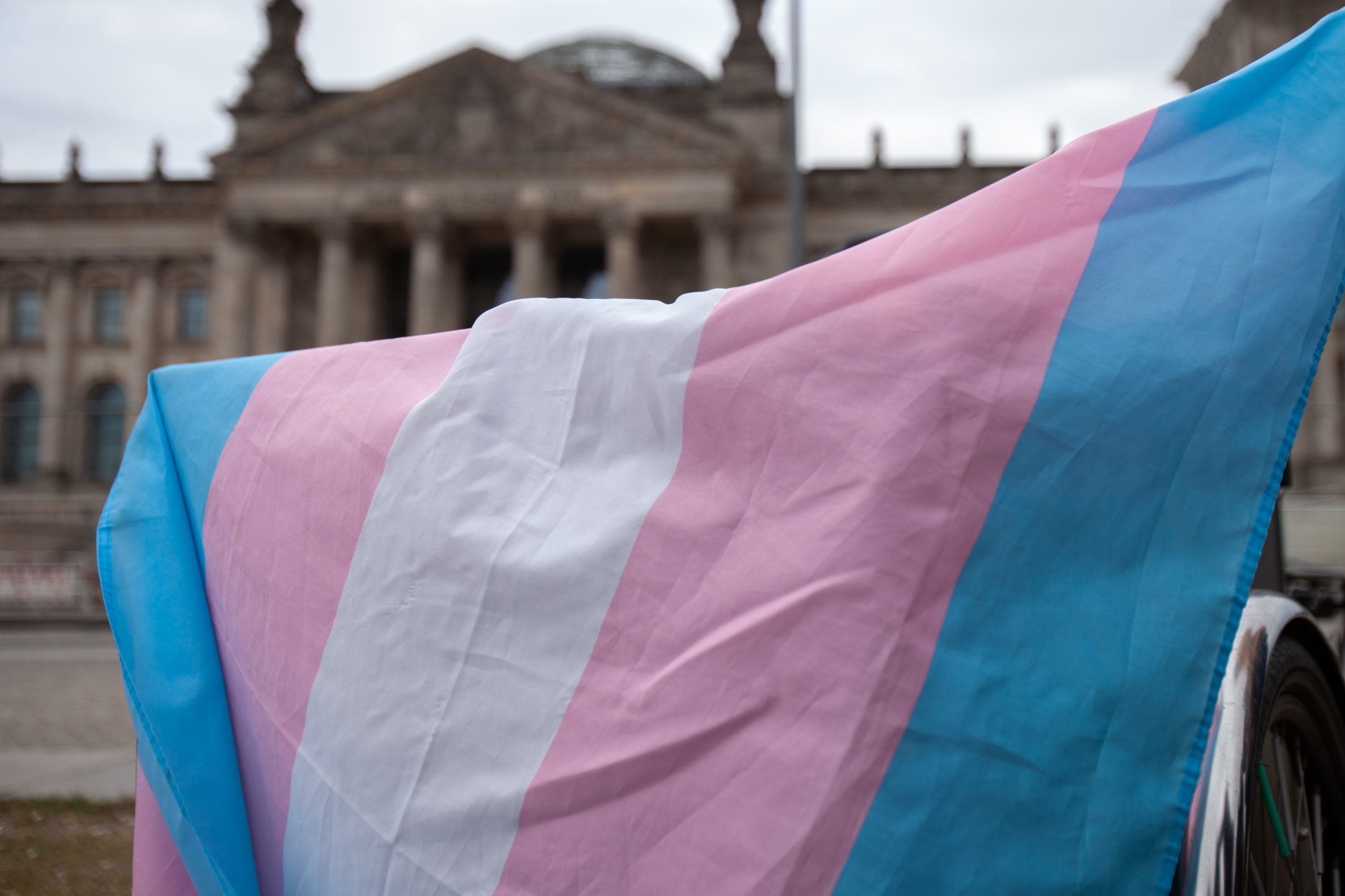 Hochgehaltene Transflagge vor dem Reichstagsgebäude